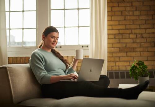 Woman sitting on couch looking at laptop
