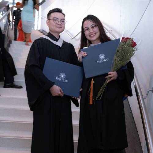 Two graduates with diplomas on stairs