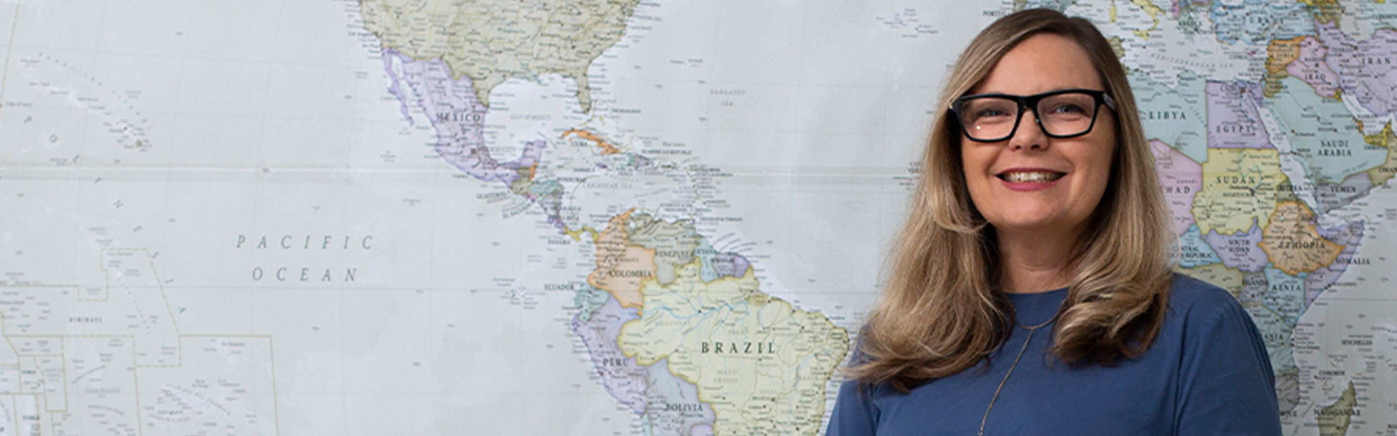 Woman with glasses standing in front of map